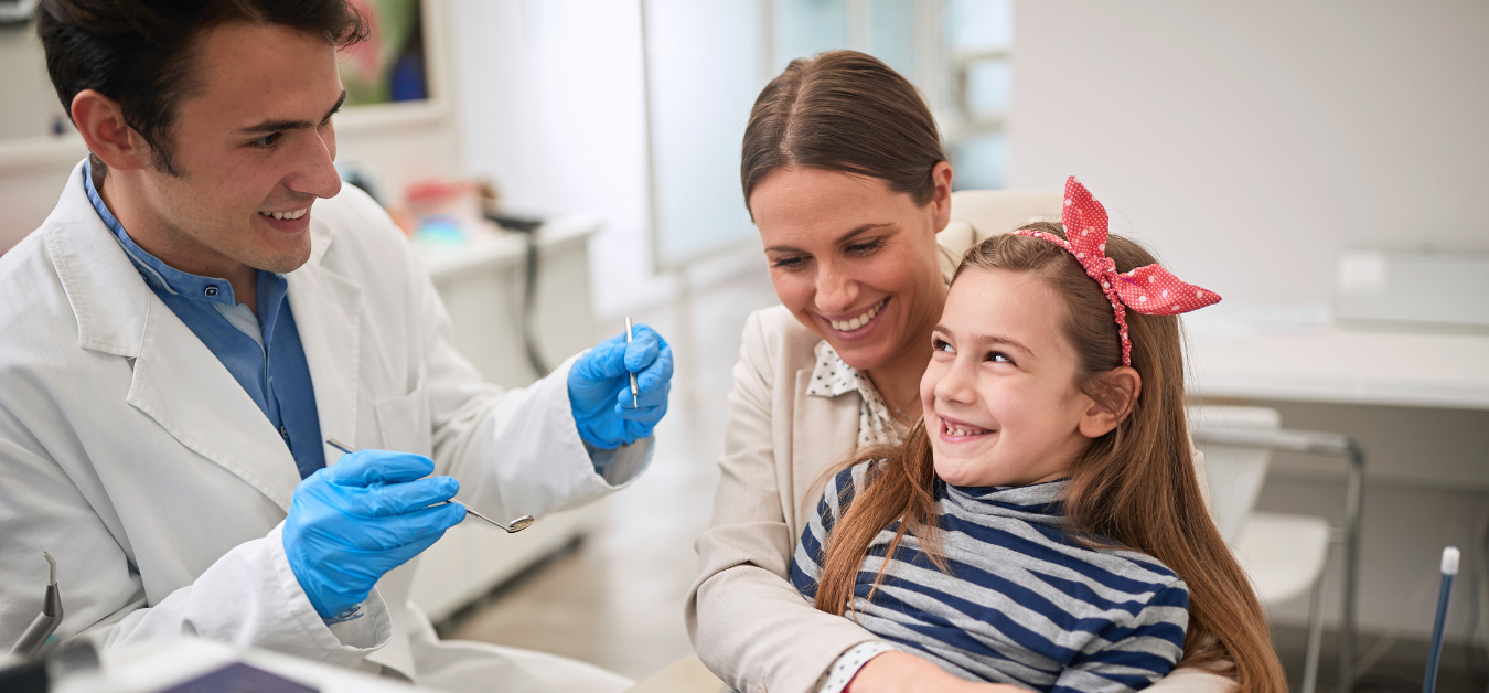 Young girl at the dentist with her mother.